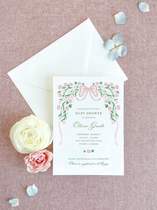 Baby shower invitation with pink floral ribbon design and personalized green script on textured pink background