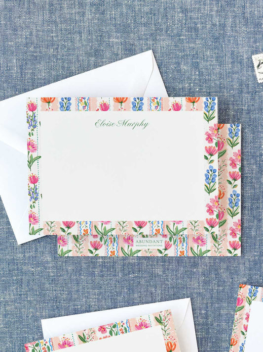 Personalized notecards featuring colorful floral borders with pink, orange, and blue blossoms on a fabric background.