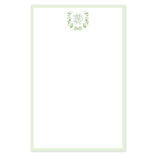 Personalized notepad with a decorative white flower wreath surrounding an interlocking monogram on a white background with a green border