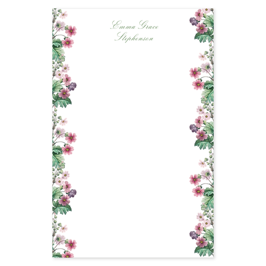 Notepad with a primrose floral border design with pink flowers and a script custom name on a white background