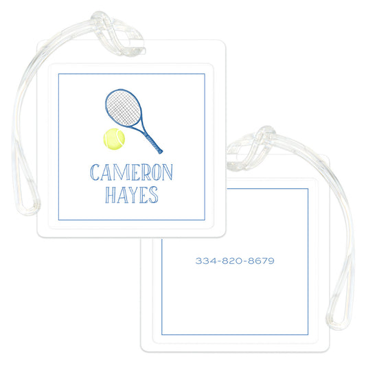Two square blue and white bag tags with clear straps, one displaying a tennis racket and ball above a personalized name, the other showing a phone number.