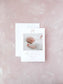 Elegant birth announcement card featuring a delicate pink bow and a soft photo of a sleeping newborn on a textured light pink background.