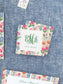 Square calling cards with colorful floral borders and elegant green monogram and name on a textured blue background