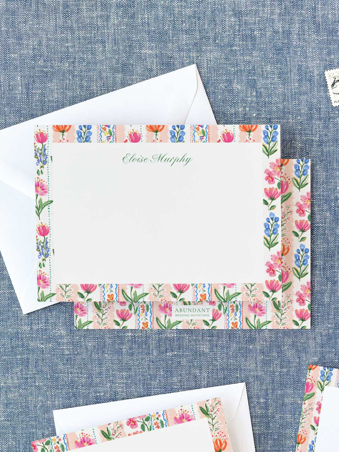 Personalized notecards featuring colorful floral borders with pink, orange, and blue blossoms on a fabric background.