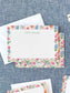 Personalized notecards featuring colorful floral borders with pink, orange, and blue blossoms on a fabric background.
