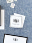 Personalized black and white calling card featuring elegant monogram and classic serif name font, displayed on textured blue fabric background.
