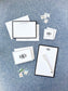 Elegant personalized stationery set featuring classic black bordered cards and notepad with monogram initials on a textured blue background.
