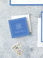 Square cobalt blue personalized calling card with elegant white monogram and cursive name on textured gray background with vintage postage stamps nearby