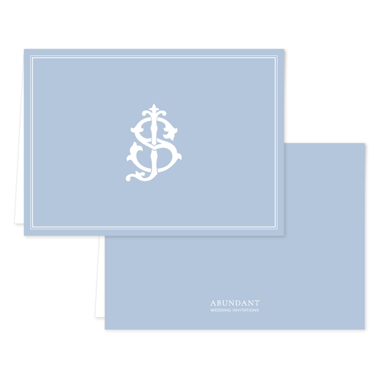 Folded notecard in pale blue with a classic white monogram design on the front and simple branding on the back, perfect for personalized stationery.