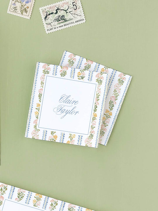 Stack of floral stripe calling cards featuring elegant script and delicate botanical border designs on a soft green background