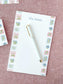 Personalized floral tile notepad with delicate pink and blue flower illustrations and a white pen on fabric background