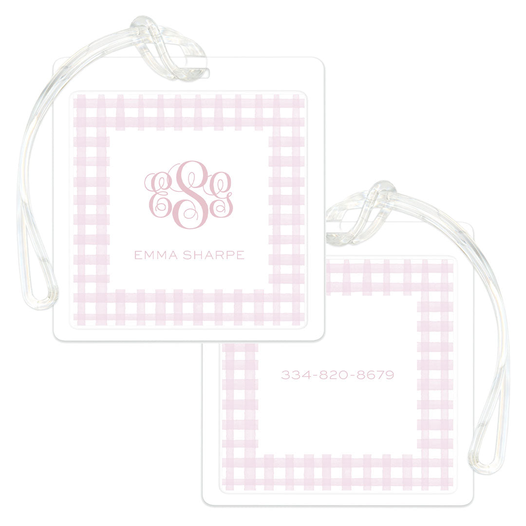 Square bag tags featuring a soft pink gingham border with personalized monogram and name on one side and contact number on the other, attached to clear plastic loops.