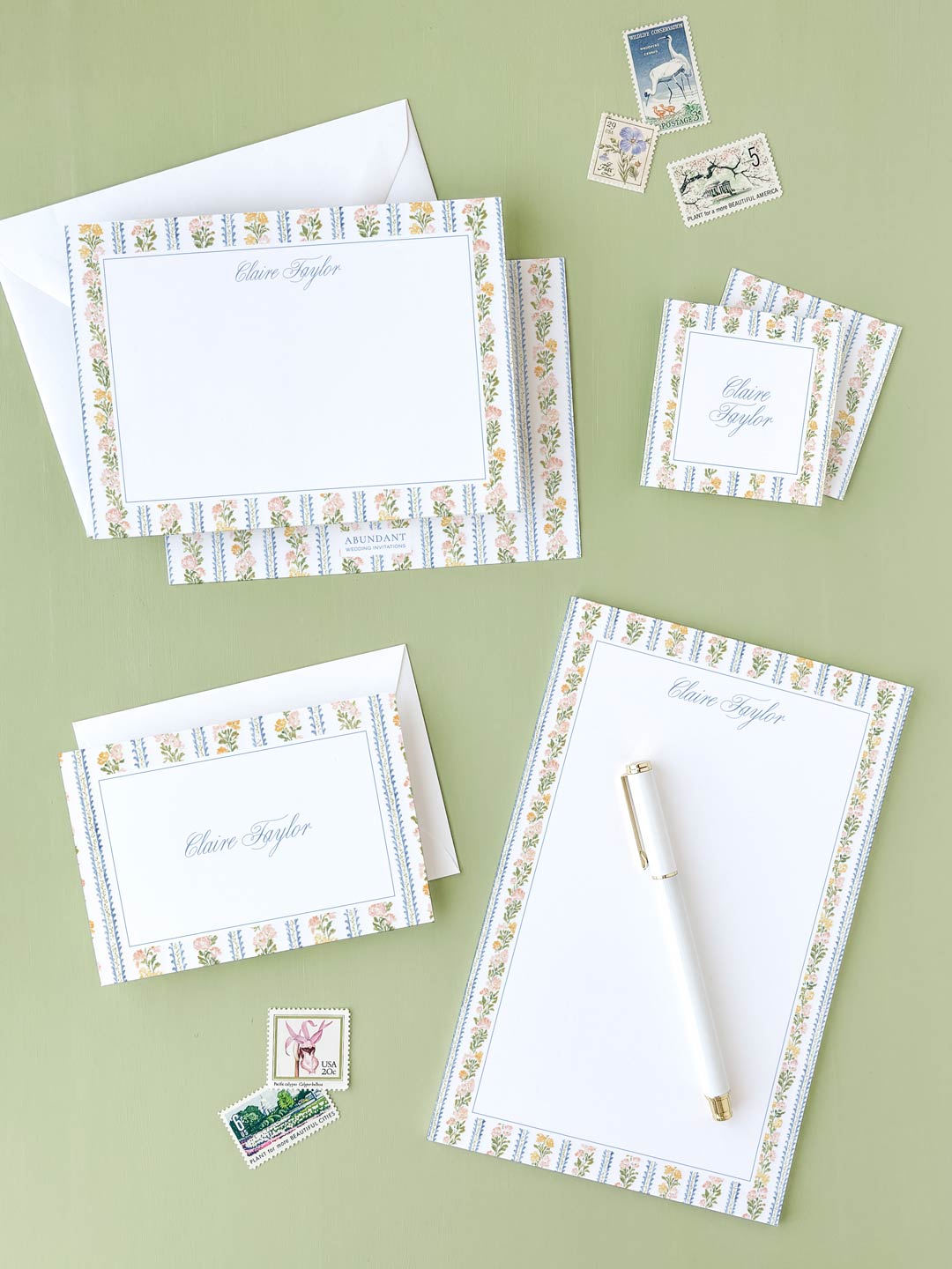 Personalized stationery set with floral striped borders, envelopes, and vintage postage stamps on green background