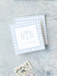 Two elegant blue gingham calling cards with monogram initials and a personalized name, displayed on a textured surface with vintage postage stamps nearby.