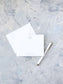 Elegant flat personalized stationery featuring a subtle blue monogram and matching envelope, styled with a white and gold pen on a textured light background.