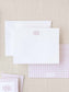 Elegant white notecard with a delicate pink monogram above, paired with matching pink gingham patterned stationery and envelope for personalized correspondence.
