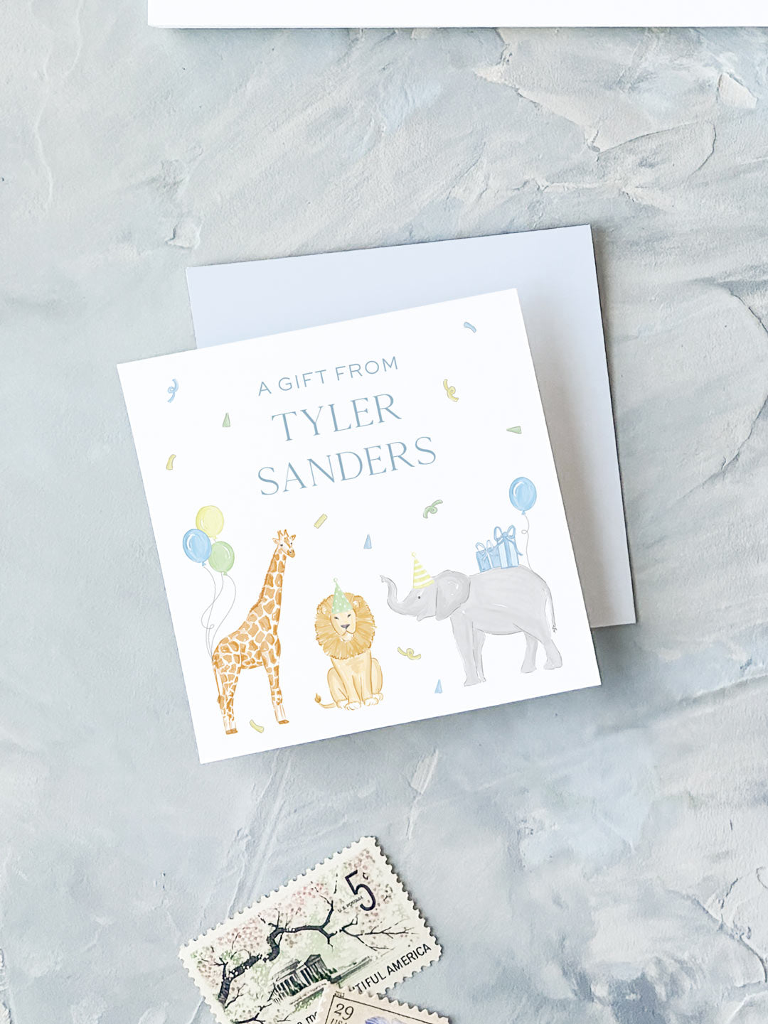 Square gift card with blue text and playful watercolor illustrations of a giraffe, lion, and elephant wearing party hats and holding balloons on a light background.
