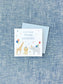 Colorful personalized calling card featuring watercolor illustrations of a giraffe, lion, and elephant wearing party hats with balloons and gifts on a textured blue background.