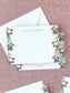 Personalized flat notecard with delicate primrose floral borders and elegant script on textured fabric background.