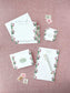 Elegant stationery set with floral borders featuring personalized notepad, envelopes, and vintage-style stamps on pink background