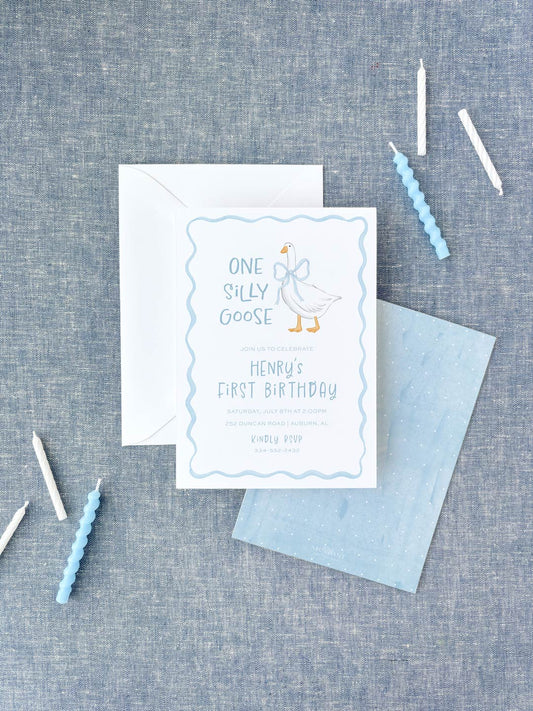 Birthday invitation featuring a playful goose illustration in soft blue tones, accompanied by matching candles and envelopes on a textured background.