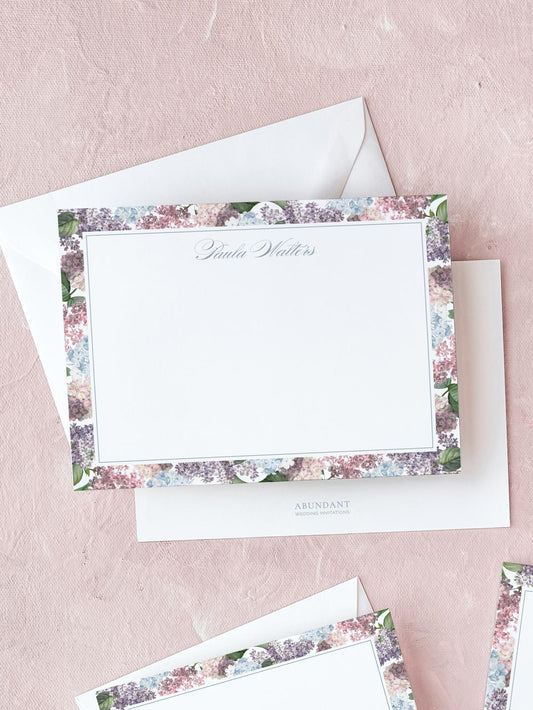 Elegant flat notecard with soft watercolor floral border and personalized calligraphy on textured pink background