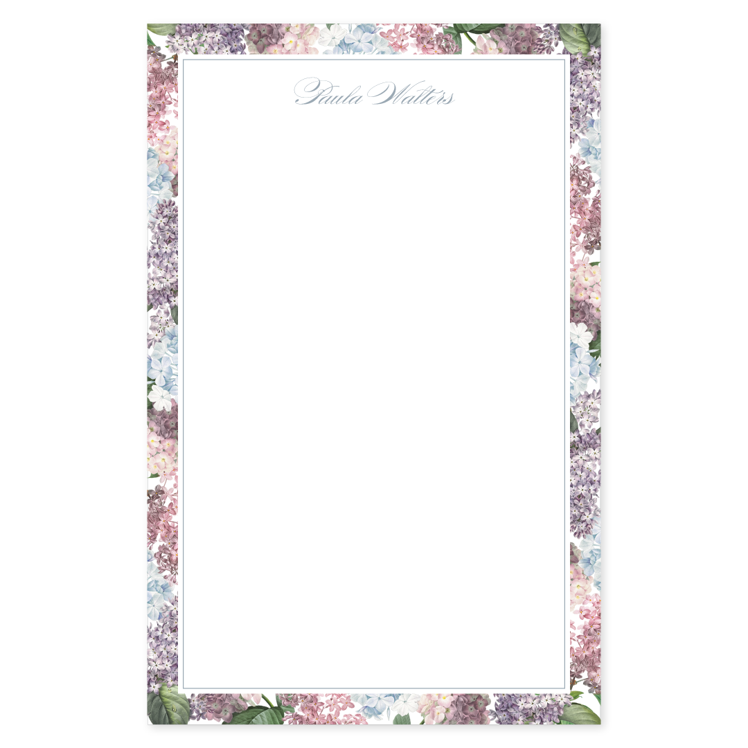Notepad with a blue, pink, and purple hydrangea floral border design with a personalized script name on a white background