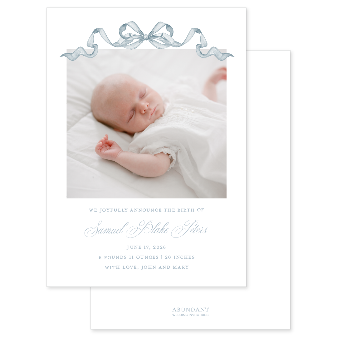 Newborn baby photo with birth announcement text and dusty blue watercolor bow on a white background