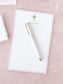 White notepad with floral cross design and elegant pen on a soft pink textured surface
