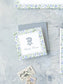 Square calling card with watercolor floral border and elegant monogram on textured gray surface