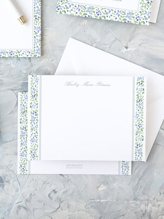Elegant personalized flat notecard with watercolor floral stripe border in soft blue and green hues on white background.